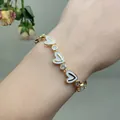 Detail of gold heart link bracelet with white enamel inlay and sparkling zircon stones - White