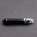 Macro shot of a black hexagonal stone pendant with a silver-tone filigree metal cap - Black Crystal