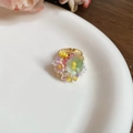 Detalle de anillo ajustable dorado con flores de resina de colores y cuentas finas - Estilo Multicolor