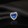 Macro shot of a blue heart crystal with silver claw setting on black silk fabric - Sapphire Blue