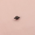 Detalle de un cierre magnético esférico de 8mm en metal gris oscuro sobre tela rosa - Imán redondo / Negro