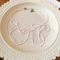 Nahaufnahme der rosa Perlenkette mit Schleifendesign auf einem Vintage-Keramikteller - Rosa Bogenschleife-Halskette