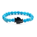 Detail of blue beaded bracelet featuring a black fish charm on a clean white background - Blue Sandstone Lake Blue Stone Penguin