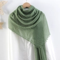 Green crinkled cotton linen scarf with fringe edges draped over white fabric clothing - Green