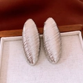 Macro shot of silver metal oval earrings with diagonal striped texture on a tray - Silver