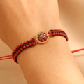 Detail van handgeweven rood en zwart basketbalarmband om pols met gouden bedel - Basketbal (11496)