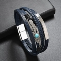 Dettaglio di un bracciale in pelle intrecciata blu scuro con piuma e turchese - Blu