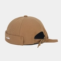 Detail of khaki canvas docker hat showing fishbone embroidery and metal buckle strap - Caramel color