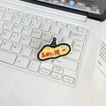 Close-up of yellow oval embroidered patch with Smile text on a white laptop keyboard - Yellow Letter