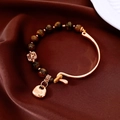 Detail of 18K gold-plated tiger eye beaded bracelet with a vintage lock pendant - Gold Brown