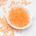 Vibrant orange frosted 6mm glass beads in a white shell dish for DIY jewelry making - 8mm Orange with Gold Glitter