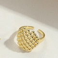 Verstellbarer goldener Herzring mit strukturierter Perlenoptik auf weißem Grund - Kupferperlen / Gold