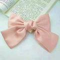 Elegant pink satin bow hair clip for women displayed on an open book background - Spring Clips / Champagne Pink