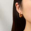 Boucles d'oreilles créoles épaisses dorées en forme de C portées par un mannequin - Doré