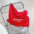 Détail du sac en toile rouge avec imprimé Sunday sur une chaise pliante transparente - Rouge