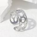 Anillo abierto de acero inoxidable plateado con diseño de cadena sobre mármol blanco - Color Acero