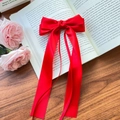 Elegant large red satin ribbon hair bow clip with long streamers on a vintage book background - Red