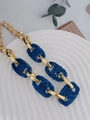Gros plan d'un collier chaîne vintage doré orné de maillons en cristaux bleus brillants - Bleu sarcelle