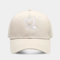Detailed view of heart embroidery on cream cotton baseball cap with curved brim - Adjustable / Beige