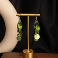 Detail of layered green resin disc drop earrings with gold hooks on black display - H3443-1 Style