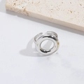 Minimalist silver cross ring shown on textured white surface with natural light - Circle / Silver