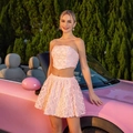 Detailansicht des rosa Blumen-Spitzenstoffs von trägerlosem Top und Plissee-Minirock-Set - XS / Rosa