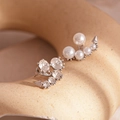 Macro view of silver asymmetric earrings with crystals and imitation pearls on ceramic - Silver Pin-Silver Asymmetric Studs