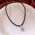 Detalle de un collar de doble capa con colgante de oso brillante en plato cerámico - Collar-Plata-Negro