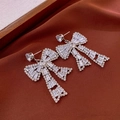 Detalle de pendientes de lazo plateados con cristales sobre fondo de terciopelo marrón - Pendientes de Lazo (Aguja de Plata-Color Plata)