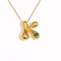 Detailed view of gold 3D bubble letter K pendant with a green heart-shaped gemstone - Letter K