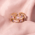 Macro-detail van gouden dubbele ring met gekleurde kristallen op roze zijde - Gouden Dubbele Rij Meerkleurige Zirkoon