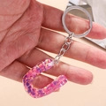 Close-up of letter U keychain with pink and purple sequins in transparent resin - Letter U