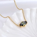 Golden necklace with olive green marquise gemstone on elegant white silk background - Virgo