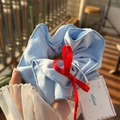 Light blue pleated fabric scrunchie with a red ribbon accent held by hand - Blue Scrunchie with Red Ribbon Bow