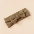 Detail of khaki knitted baby headband with a large textured bow on a plain background - Khaki