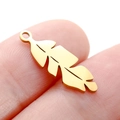 Hollow leaf pendant in gold stainless steel shown on a finger for scale and detail - DY746 Feather / Gold