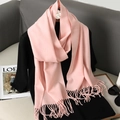 Detail van roze kasjmierachtige sjaal met lange kwastjes gedrapeerd op een zwarte top - Roze