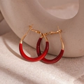 Primer plano de pendientes de aro dorados esmaltados en burdeos sobre soporte - Aguja de Plata - Aros Rojos Pequeños (24mm)