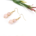 Close-up of pink crystal beads wrapped in gold wire with a floral background setting - Gold + Rose Quartz