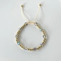 Close-up of colorful crystal cube beads and gold spheres on a braided adjustable bracelet - Rainbow Multicolor