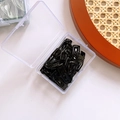 Detail of black metal hair clips organized in a clear plastic storage box on a neutral background - Black Square