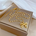 Close-up of golden butterfly pendant with sparkling cubic zirconia on a silk background - Gold Bowknot Style (J331)