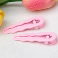 Pink 6cm wave-shaped teardrop hair clips with matte finish in a floral setting - Pink