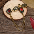 Vintage bijenbroche met rode edelsteen en kwastjes op houten ondergrond - Rode kristallen bijenkettingbroche