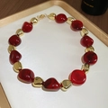 Detail of acrylic dyed irregular red and gold beads necklace on a luxury white tray - Necklace / Red