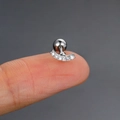 Silver stainless steel curved bar helix stud with sparkling zircons shown on a fingertip - CC129-1 Silver Curved Bar