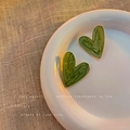 Vintage green heart-shaped earrings with marble texture and gold edges on white plate - Mustard Green Enamel Heart