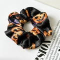 Gros plan d'un chouchou en satin noir avec motifs de citrouilles d'Halloween orange - Citrouille Noire
