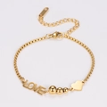 Detalle macro de la pulsera Love dorada con cuentas pulidas y cadena ajustable fina - Dorado