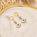 Close-up of golden evil eye earrings on marble tray with natural wheat decoration - Gold Eyelash Eye Design
